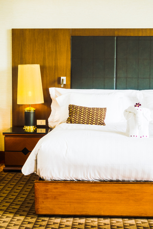 Beautiful luxury white pillow on bed and light lamp beside decoration in hotel bedroom interior warm white balance processing