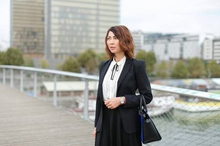 ジャーナリスト ビジネス服を着た女性が仕事に行く 黒いジャケットのスカートと白いブラウスを着た笑顔の中年アメリカ人女性 が モバイルで友人と話しています 革新的な技術やガジェットやファッショナブルな女性の衣装の概念 の写真素材 画像素材 Image