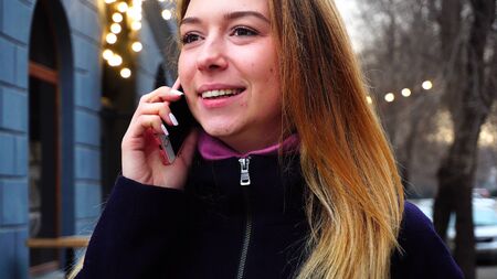 かわいい女性がカフェの近くに立って 電話 クローズアップ写真で話します 女の子は黒いコートと紫色のスカーフを着ています インターネットによる電話 作業のための現代技術無料通話やアプリの概念 の写真素材 画像素材 Image