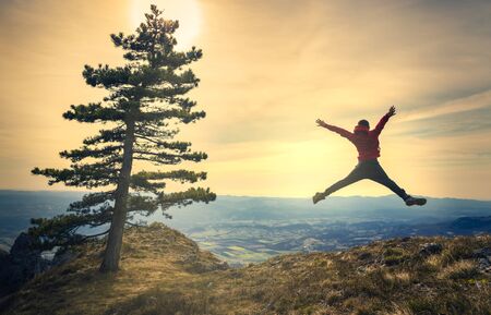 Jeune homme actif se sentant libre. vivez la liberté au cœur de la nature. sauter haut au sommet de la montagne. Banque d'images