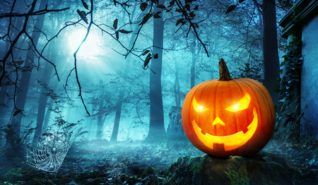 Moonlight lanterns: Glowing Jack o lantern in a creepy old overgrown cemetery with cool blue moonlight