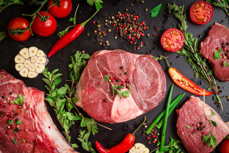 different types of steaks set assorted raw meat on a black chalk