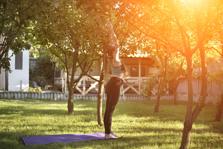 Pregnant woman in the garden practices yoga, greeting the sun. Summer morning.