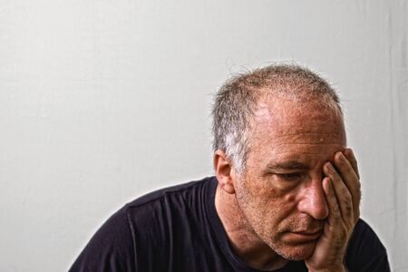 beautifully detailed real portrait of haggared looking adult white man holding his head as if having a headache or is in deep dispair