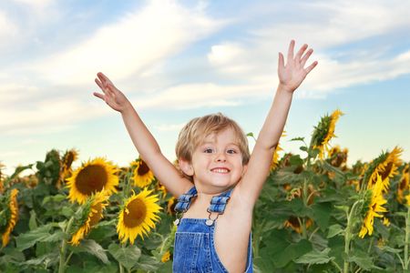 a young boy standing in front of a field of sunflowers