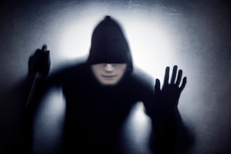 Man in a mask with a knife behind a dusty scratched glass
