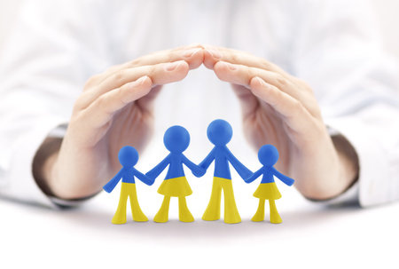 Family figurines with the colors of the Ukrainian flag covered by hands