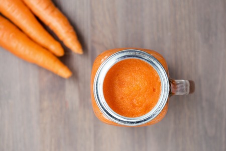 a carrot: Trà cà rốt khỏe mạnh trong bình với cà rốt trên nền bằng gỗ. Shallow dof Kho ảnh
