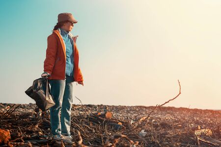 A Young Caucasian Female Volunteer In A Jacket Holding A Garbage