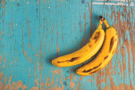 banana: Hai quả chuối chín già trên bàn gỗ mộc mạc, nhìn từ trên xuống