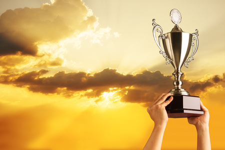 Winning team raise trophy cup with background of sky of light ray