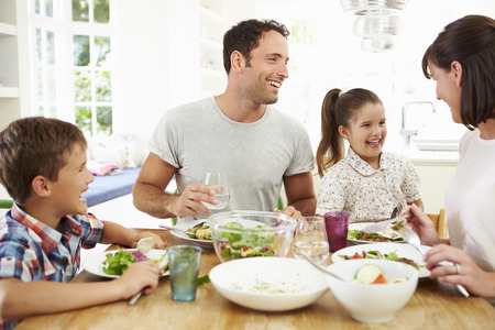 Familie, die zusammen Mahlzeit um Küchentisch isst