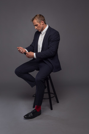 elegant young fashion man in tuxedo sitting on the chair Фото со стока