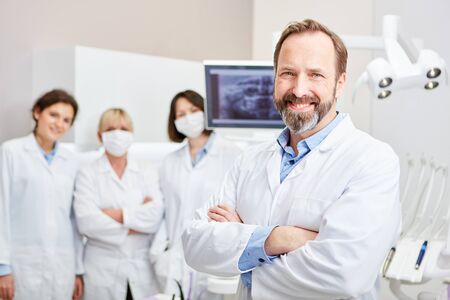 Uśmiechnięty dentysta z zespołem do szkolenia w klinice dentystycznej