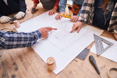 Architects And Craftsmen Look At A Floor Plan For A House Building Project