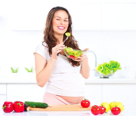 Pregnant woman eating vegetable salad. Cooking vegetables Stock Photo