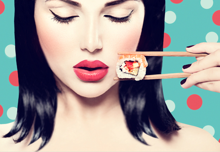 Belle femme tenant des baguettes avec rouleau de sushi Photo stock
