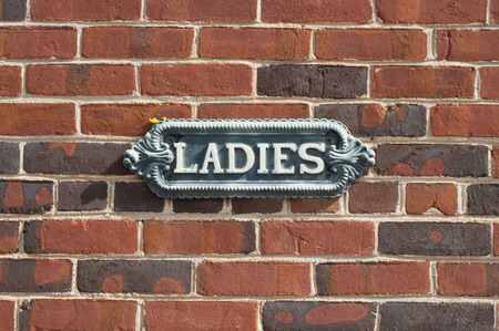 old antique ladies restroom sign on red brick wall stock photo