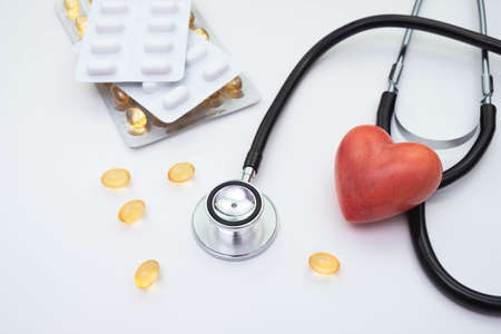 Vitamins and pills stethoscope and red artificial heart on a white background on the table