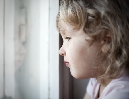 sad lonely: Sad little girl looking at window