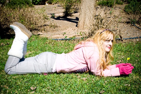 Young girl lying in grass holding a flower