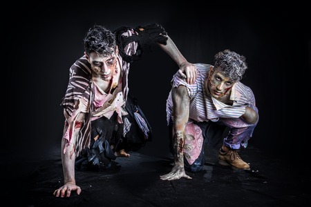 Two male zombies crawling on their knees, on black smoky background, looking at camera. Halloween theme - 45943723