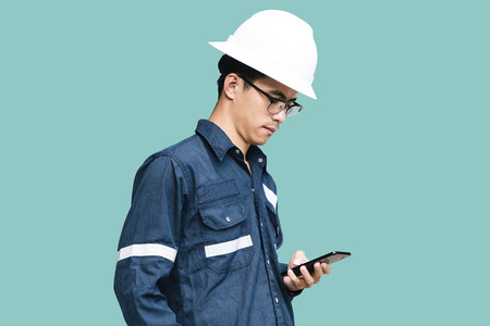 緑に隔離されたスマートフォンを使用して 白いヘルメット 眼鏡と青のワーキングシャツスーツでエンジニアや技術者 の写真素材 画像素材 Image 4096