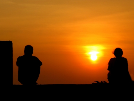 A metaphorical image of the silhouettes of a seperated couple on the backdrop of a sunset.                                - 24041291