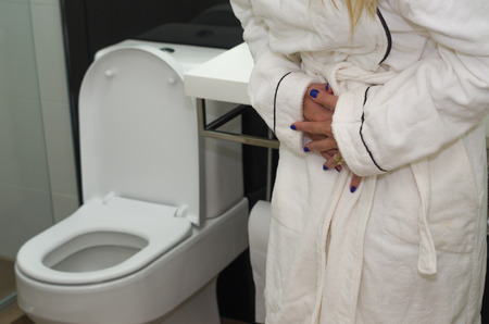 Young blonde woman getting sick, with nausea in the bathroom.