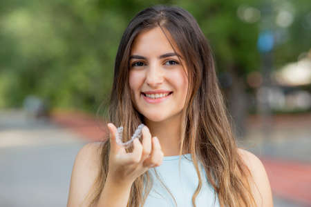 Piękna uśmiechnięta turczynka trzyma naramiennik invisalign