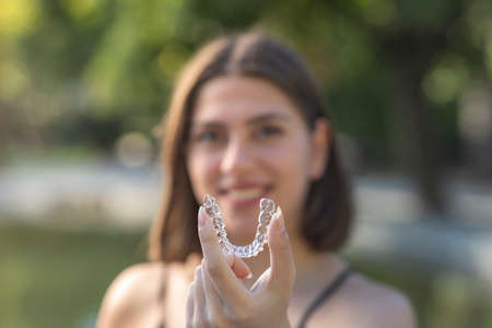 Piękna uśmiechnięta turczynka trzyma naramiennik invisalign
