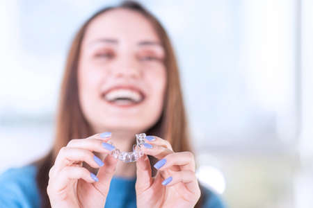 Beautiful smiling turkish woman is holding an invisalign bracer, includes copy space Zdjęcie Seryjne