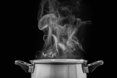 Steam over cooking pot in kitchen on dark background