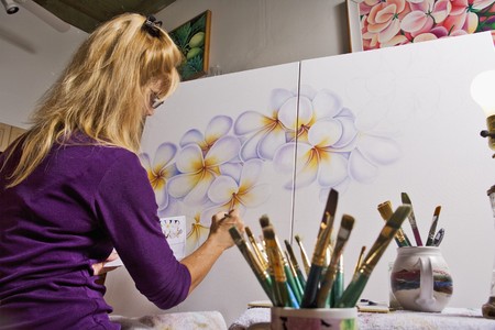 A female artist painting on canvas in her studio Фото со стока