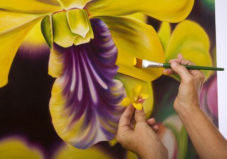 hands of a female artist painting orchids on canvas in her studio