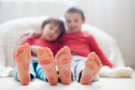 Little kids feet covered with prints from kisses children playing on tablet