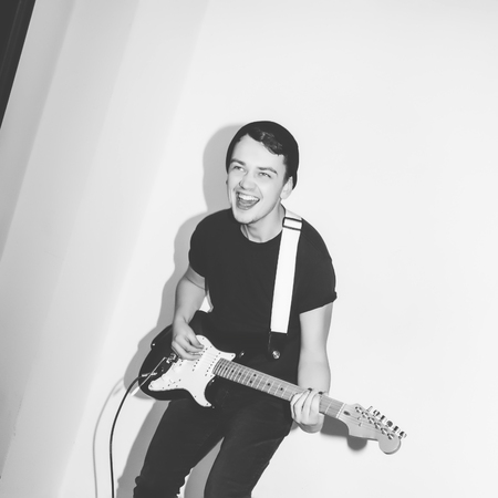 若い音楽家岩ギター プレーヤー ジャンプ スタジオで情熱を持って素晴れらしい奇抜なファッション スタイリッシュなロッキーの感情的な男 黒と白が基調します の写真素材 画像素材 Image 70326297