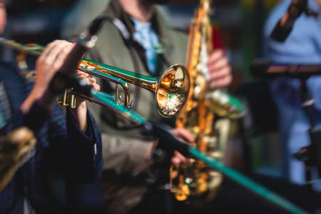 Concert view of a male trumpeter, professional trumpet player with vocalist and musical during jazz band performing in the background
