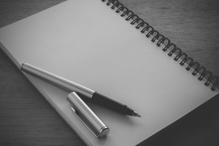 Paper notebook and pen on a table with filter effect retro vintage style