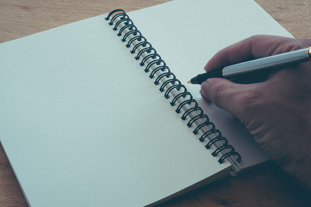 Retro effect faded and toned image of a writing a note with a fountain pen