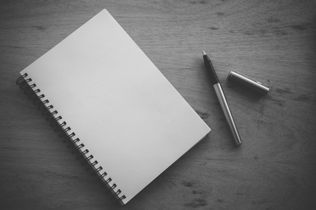 Paper notebook and pen on a table with filter effect retro vintage style