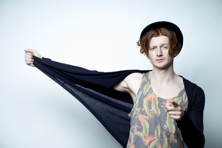 かわいい赤髪若いおしゃれなひげを剃っていないスタイリッシュな男性一カラフルな花柄プリントの黒い帽子と白い背景 画像の垂直方向のスタジオに立って青ジャージと下着で の写真素材 画像素材 Image