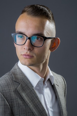 オタク メガネとスタジオの背景にジャケットでスタイリッシュな髪型の若いファッション実業家 の写真素材 画像素材 Image