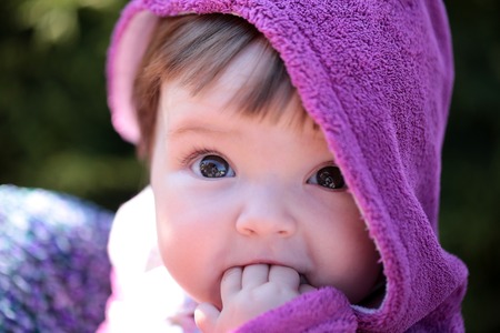 small cute baby girl with pretty face and funny eyes in hood stock