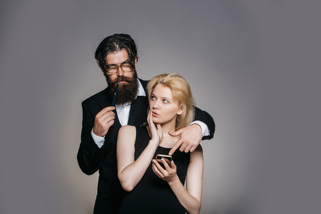 美しいカップルの若い可愛いセクシーな思慮深い女性保有携帯電話とグラス ペンを支える彼女のスタジオで髭のハンサムな男 の写真素材 画像素材 Image