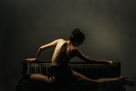 Stock Photo Young Girl Or Woman Dancer With Sexy Flexible Body Of Ballerina And Naked Back Posing On Old Retro Wooden Piano On Grey Background Stock Photo Young Girl Or Woman Dancer With Sexy Flexible Body Of Ballerina And Naked Back Posing On Old Retro Wooden Piano On Grey Background