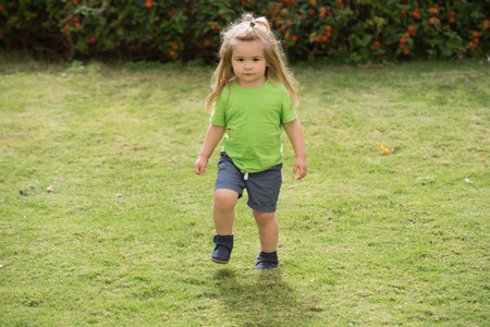 Kleiner Junge im grünen Hemd läuft und kurze Hosen, Kind i Kleiner Junge im grünen Hemd läuft und kurze Hosen, Kind i