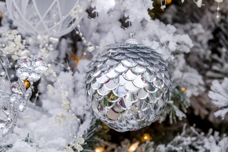 close up of shiny silver christmas ornament hanging on frosted frosted christmas ornaments
