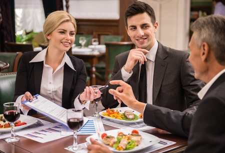 Überzeugte Geschäftspartner in den Klagen, die Vertrag während des Business-Lunchs besprechen.