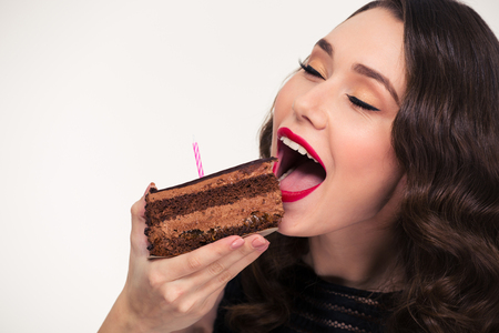 Gros Plan De Jolie Fille Bouclee Mignonne Avec Coiffure Retro Manger Morceau De Gateau D Anniversaire Au Chocolat Avec Bougie Sur Fond Blanc Banque D Images Et Photos Libres De Droits Image